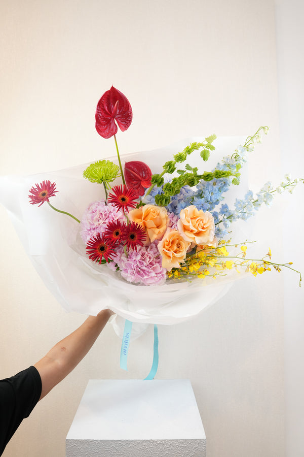 Bouquet of colorful flowers being held by a person against a white background