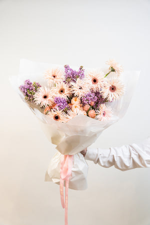 Soft peach tones meet rich purples in Velvet Dusk—a hand-tied bouquet that captures the quiet beauty of twilight. Elegant, romantic, and thoughtfully composed, it's a floral poem for moments that deserve to be remembered.