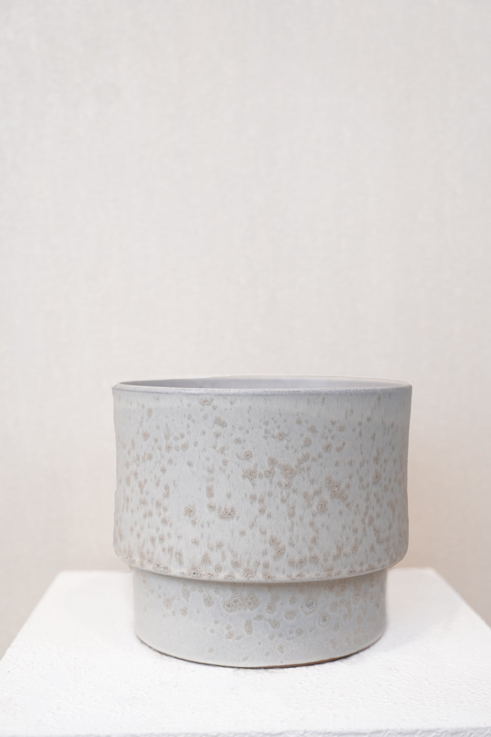 Speckled gray ceramic planter on a white surface with a light beige background