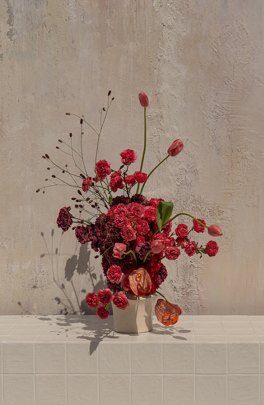Elara - deep red roses, burgundy carnations, and blush pink tulips with physalis in a cream ceramic