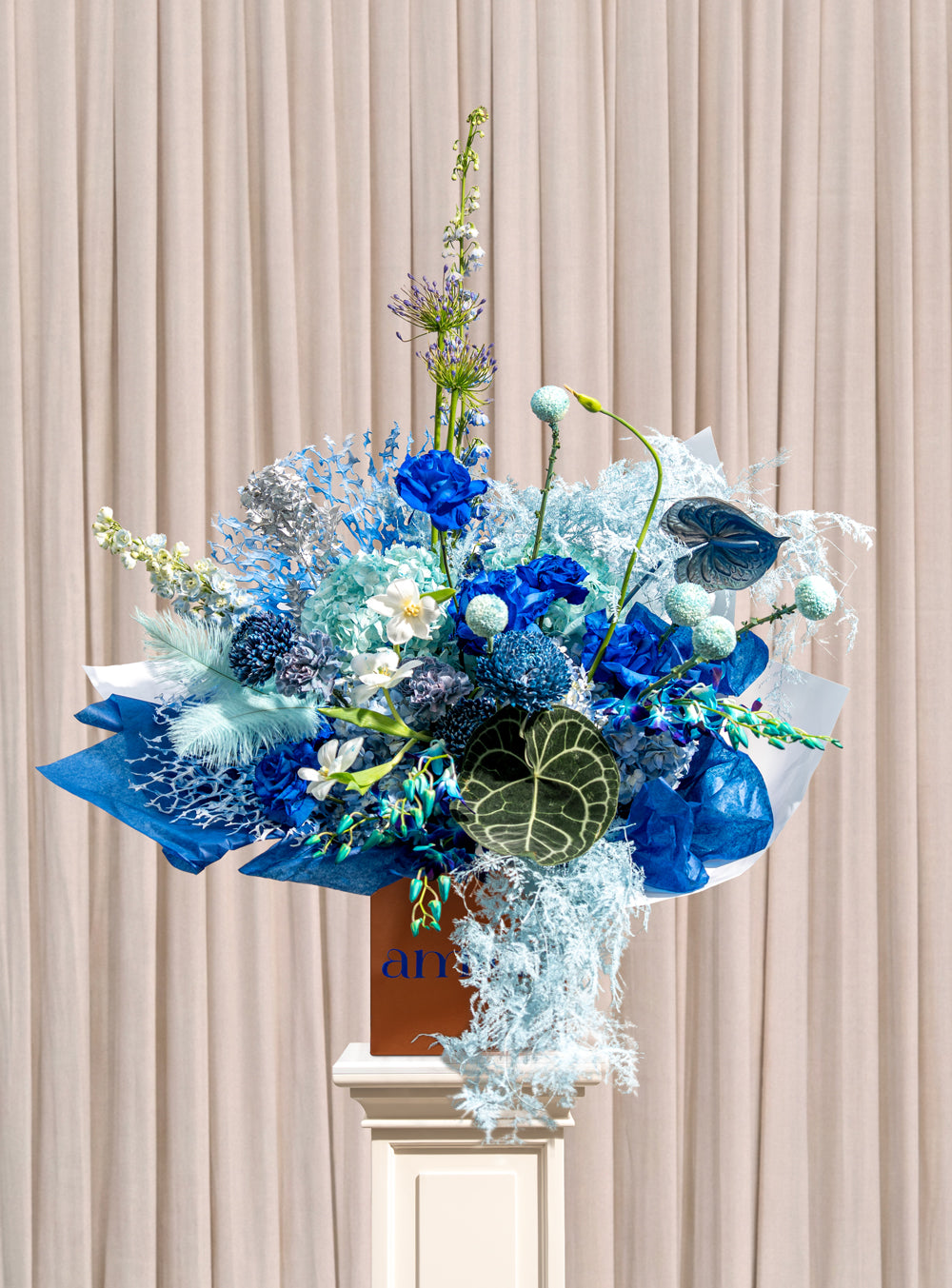 Bleu all-blue arrangement with cobalt roses, blue hydrangea, agapanthus and silvered foliage in a copper Amicis box