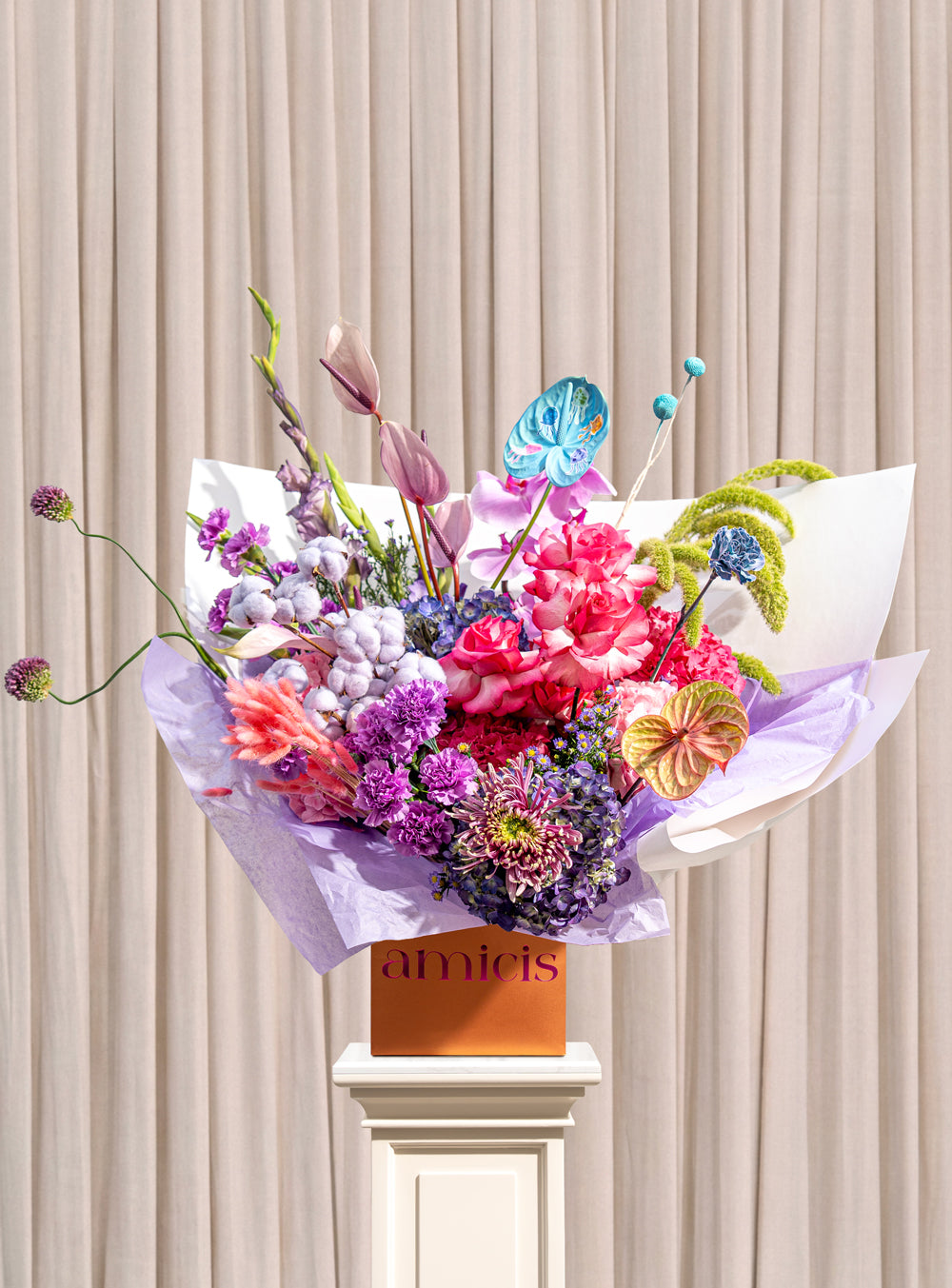 Lumiere violet and pink arrangement with magenta roses, purple carnations, blue anthurium and green amaranthus in a copper Amicis box