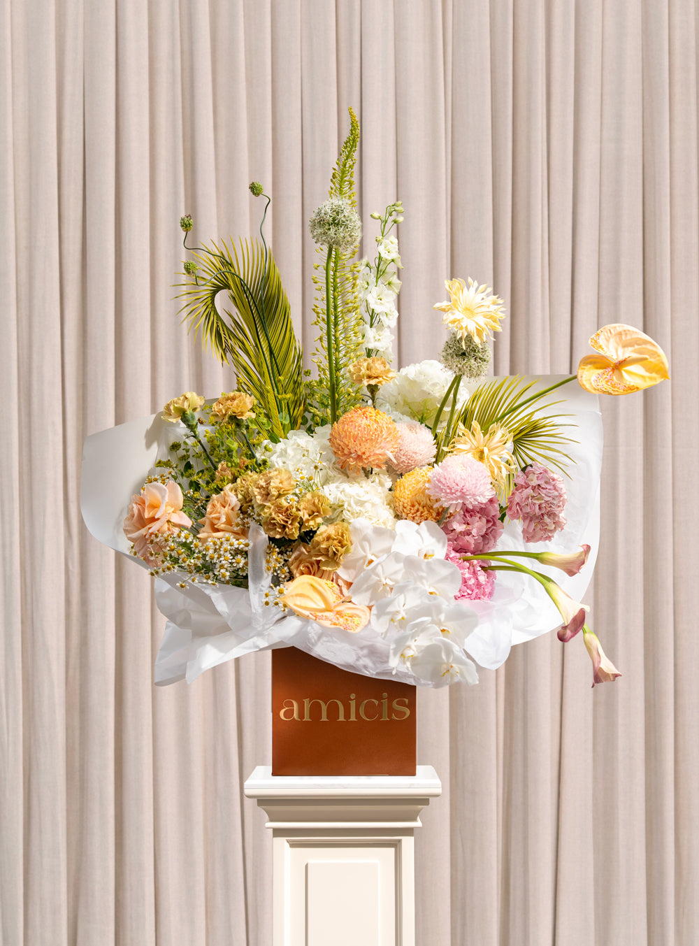 Sylvan peach and cream arrangement with peach chrysanthemums, white phalaenopsis orchids, carnations, roses and palm fronds in a copper Amicis box
