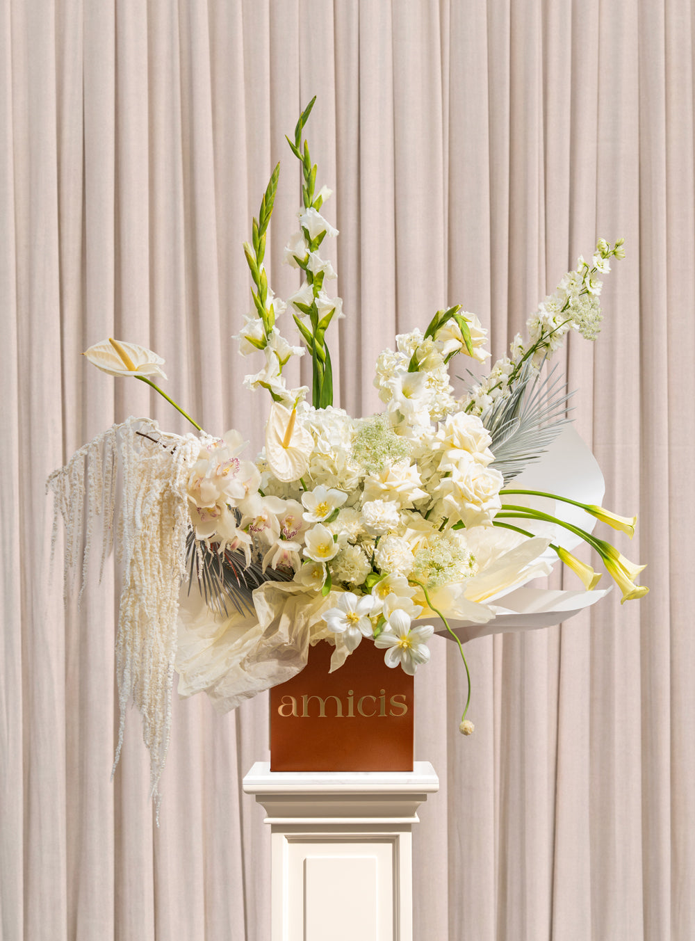 Fleur Blanche all-white arrangement with white gladiolus, roses, cymbidium orchids, calla lilies and cascading cream amaranthus in a copper Amicis box