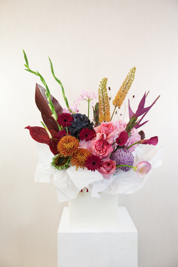 Colorful bouquet of flowers on a white pedestal against a light background