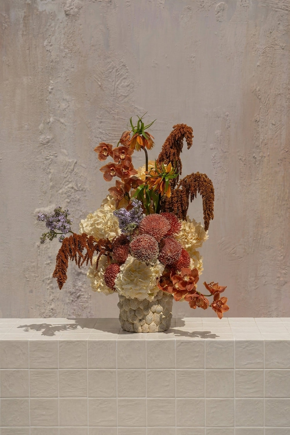 Bespoke - rusty orange orchids, fritillaria, and amaranthus with cream hydrangeas and burgundy chrysanthemums in a textured ceramic vase by Amicis