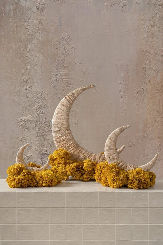 Moon Flower Structure - vibrant yellow marigolds around three natural fiber crescent moons on a