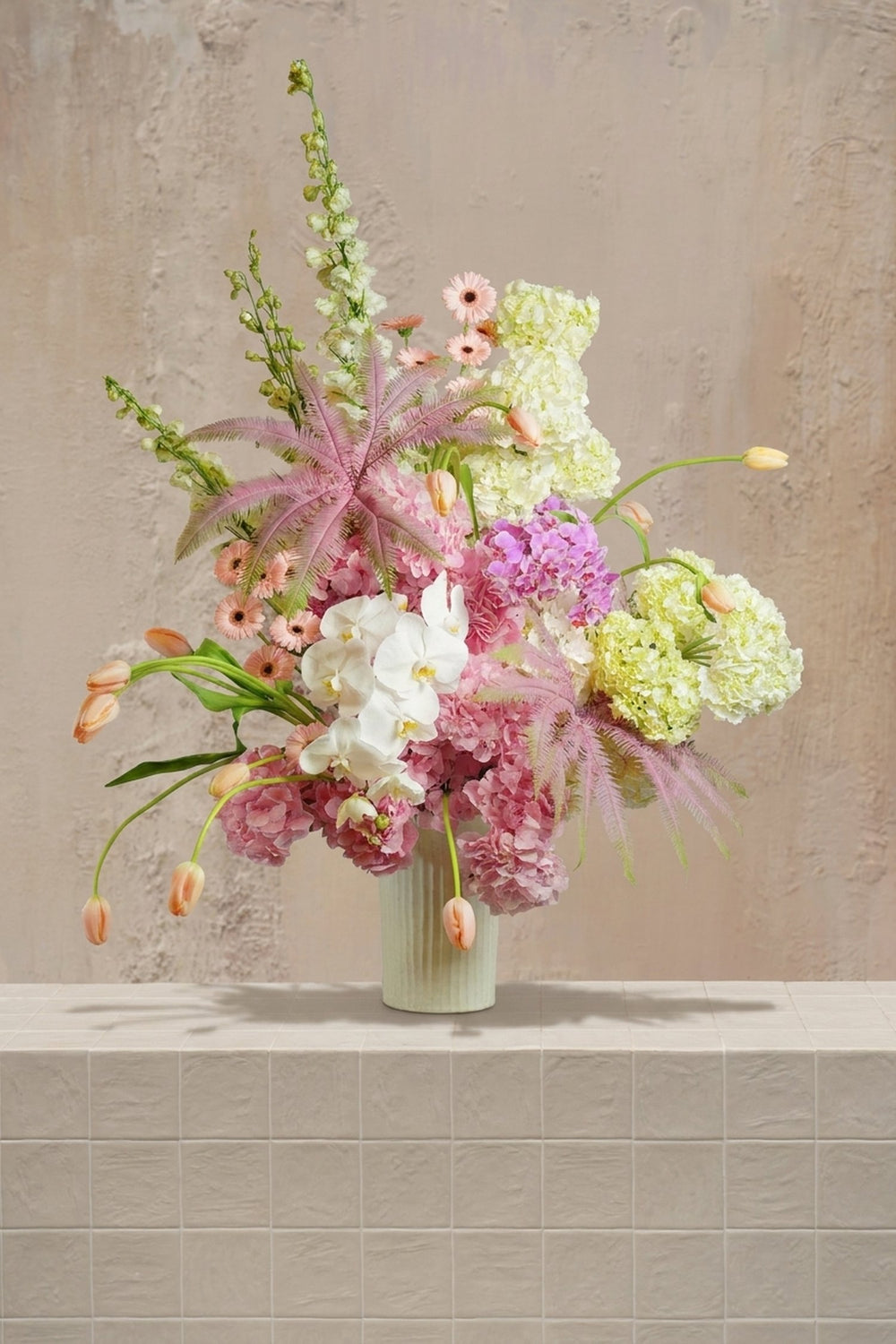 Blush Elegance - white orchids, blush hydrangeas, peach tulips, green delphinium, and pink fern in a ribbed cream vase by Amicis