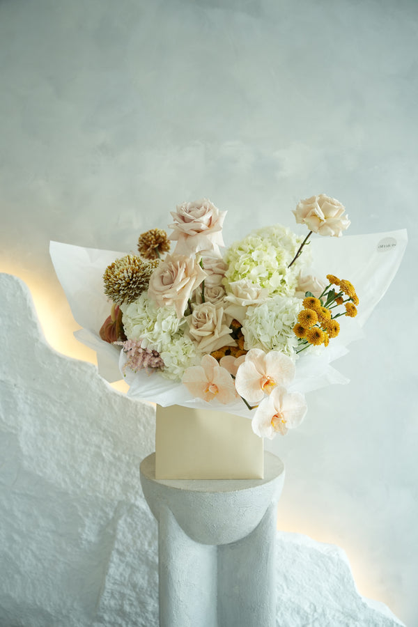 A serene symphony of ivory hydrangeas, muted blush roses, and delicate orchids—this bouquet captures timeless grace with every bloom. Perfectly composed for moments that call for quiet luxury and refined beauty.