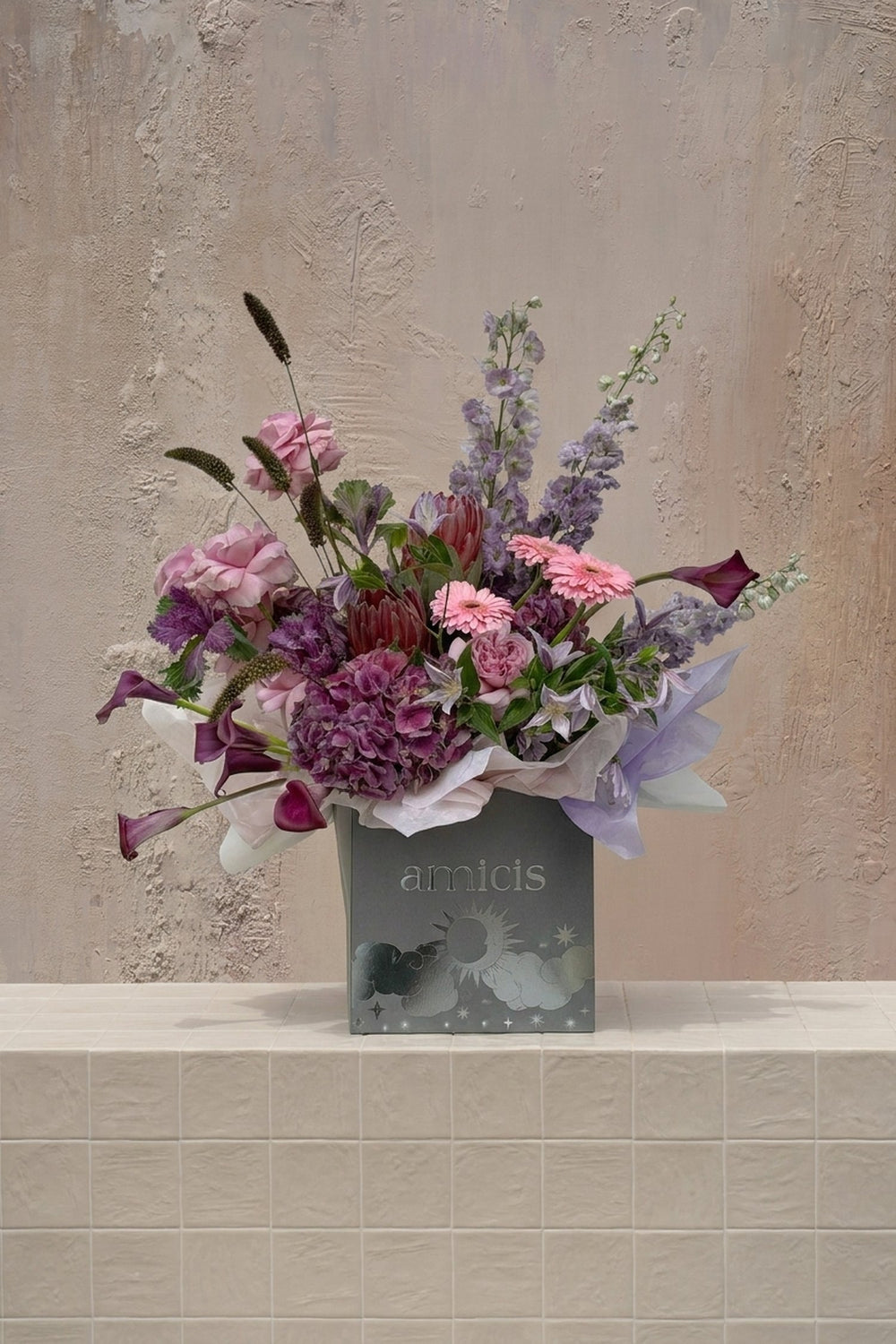 Eclipse 4 - pink roses, gerberas, purple hydrangeas, lavender delphinium, and burgundy calla lilies in a grey gift box by Amicis