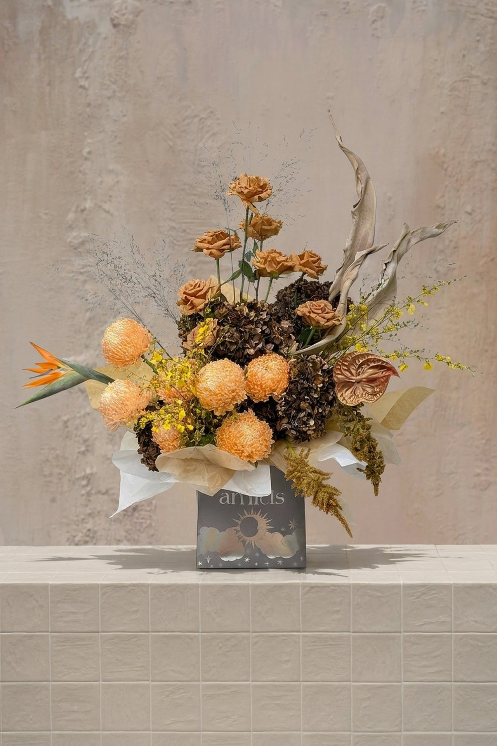 Eclipse 6 - vibrant orange protea, terracotta roses, bird of paradise, and bronze anthurium in a decorative gift box by Amicis