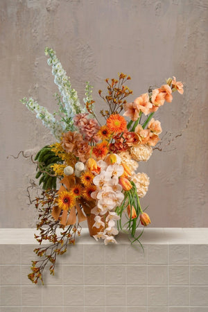 Engrande - vibrant peach, orange, and cream amaryllis, gerberas, orchids, and delphinium with green amaranthus in a terracotta vase by Amicis