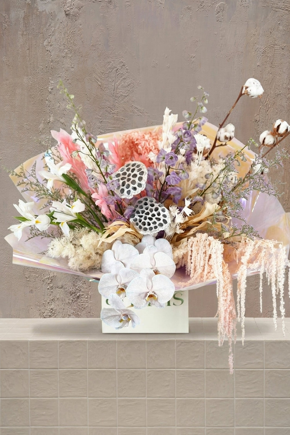 Opaline Muse - white orchids, irises, blush pink carnations, lavender flowers, and dried elements in an iridescent bouquet in a white box by Amicis.