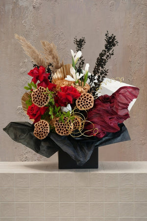 Golden Prairie - deep red roses, white irises, dried lotus pods, pampas & palm leaves in a black box with red fabric by Amicis
