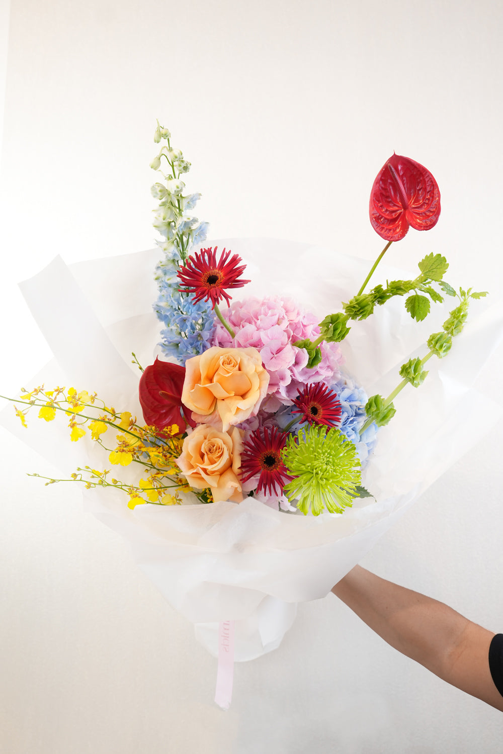 Bouquet of colorful flowers held by a person against a white background