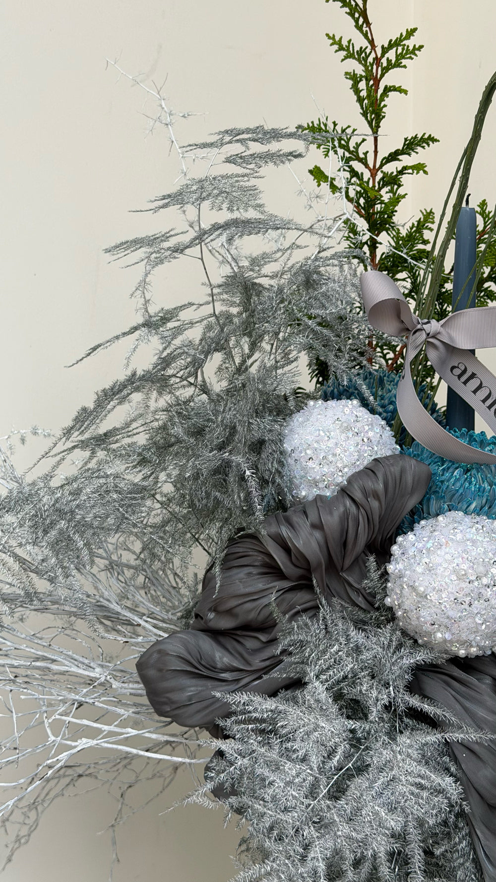 Sparkle Holidays 06 - silver foliage, dark green pine, white & teal hydrangeas, silver anthurium, and dark blue candles in a dark ceramic vase by Amicis