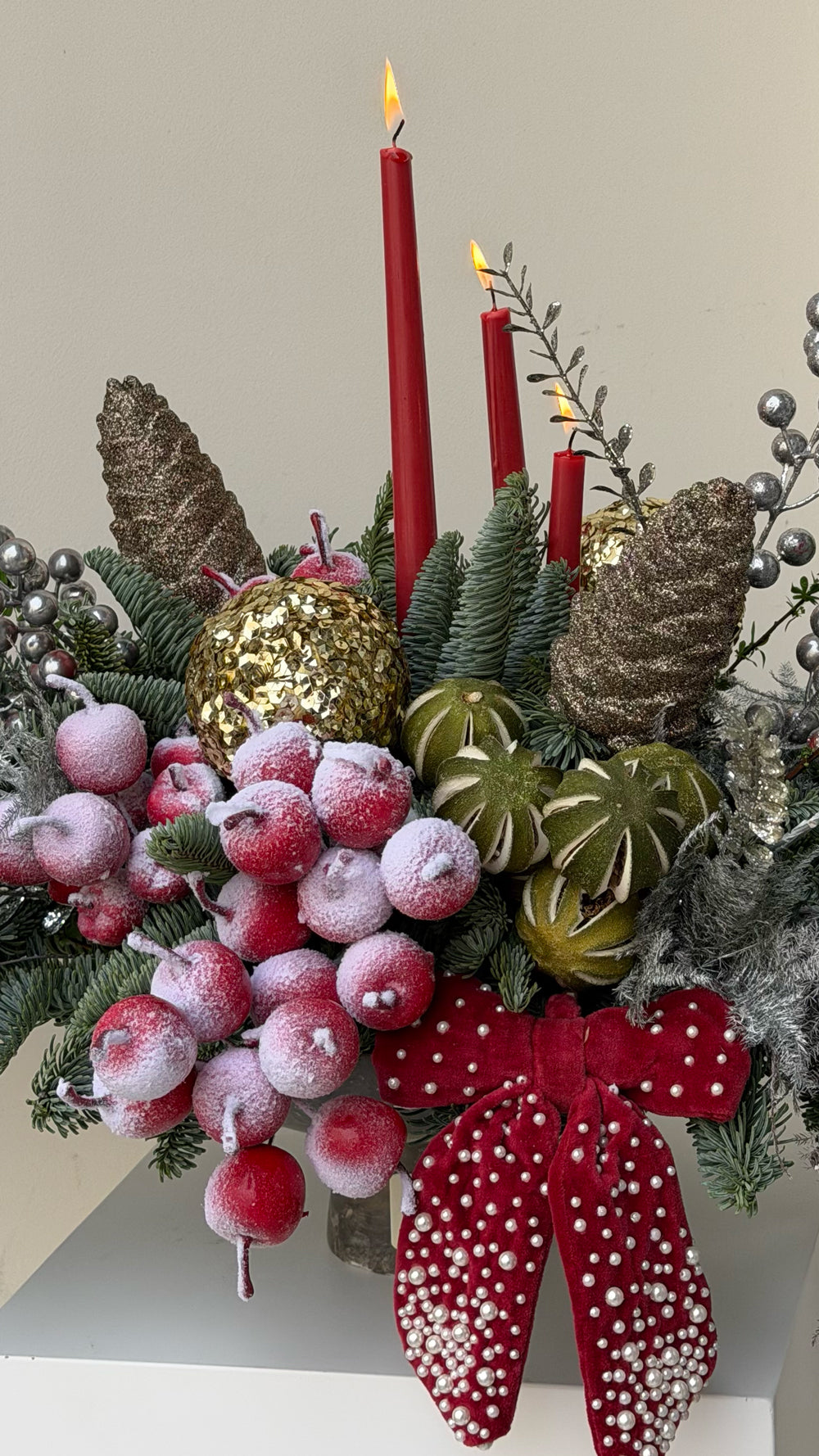 Sparkle Holidays 08 - deep red candles, frosted red berries, pine branches, pinecones, and silver accents in a dark bronze bowl by Amicis