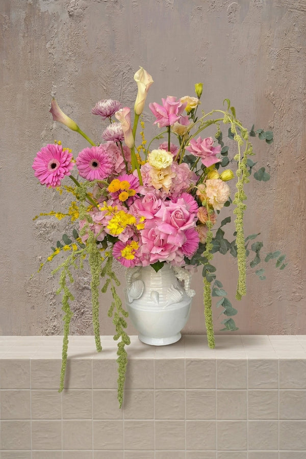 Mermaid - pink roses, gerberas, hydrangeas, cream calla lilies, yellow accents, and trailing amaranthus in a white ceramic vase by Amicis