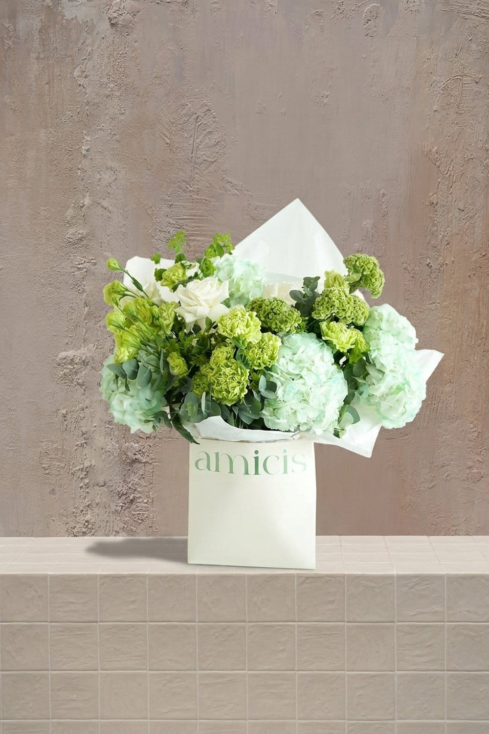 Mint Whisper - mint green hydrangeas, white roses, green carnations, and eucalyptus in a white Amicis gift bag by Amicis