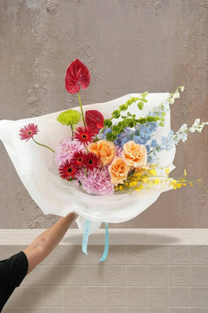 Bouquet of colorful flowers being held by a person against a white background