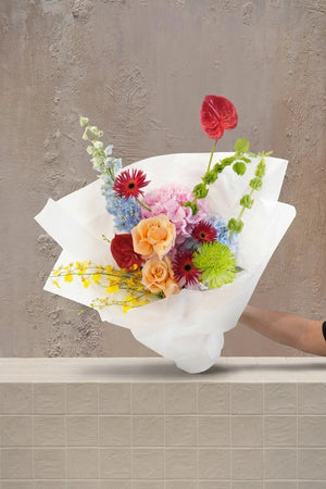 Bouquet of colorful flowers held by a person against a white background