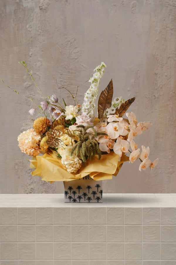 Savanna Bloom - peach orchids, blush roses, lavender tulips, and gold anthurium with white blooms in a palm-patterned gift box by Amicis