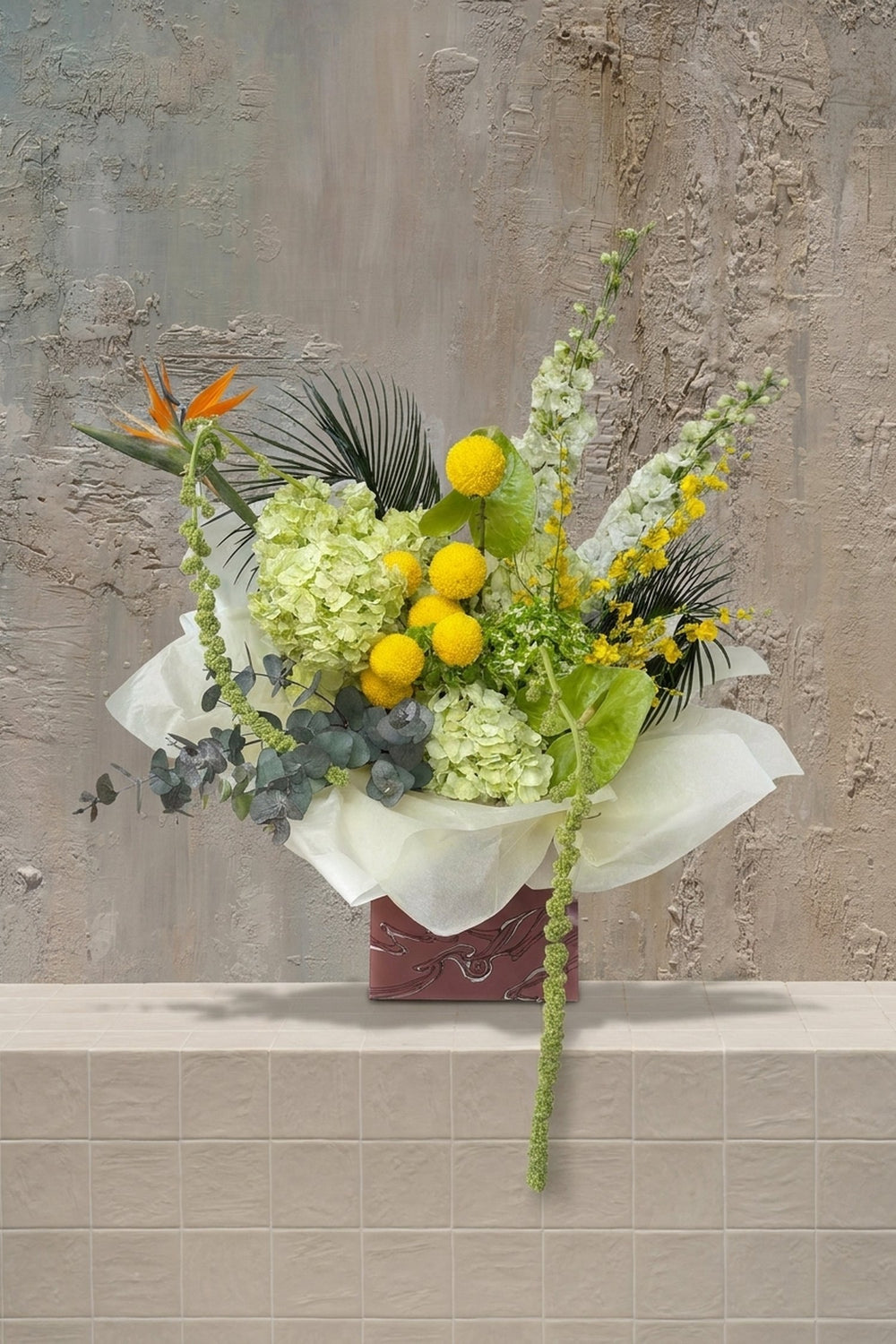 Sienna Grace - orange Bird of Paradise, yellow craspedia, lime hydrangeas, white snapdragons, and trailing amaranthus in a decorative gift box by Amicis
