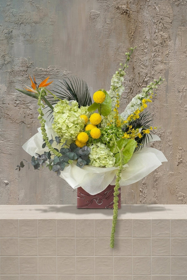 Sienna Grace - orange Bird of Paradise, yellow craspedia, lime hydrangeas, white snapdragons, and trailing amaranthus in a decorative gift box by Amicis
