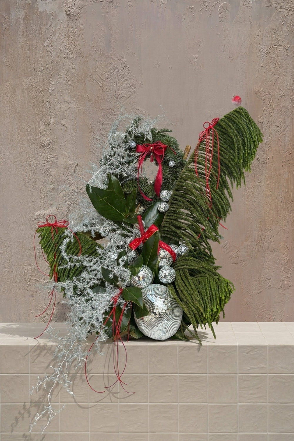 Sparkle Holidays 02 - Bold holiday arrangement with deep green pine, shimmering silver foliage, red ribbons, and disco ball ornaments by Amicis
