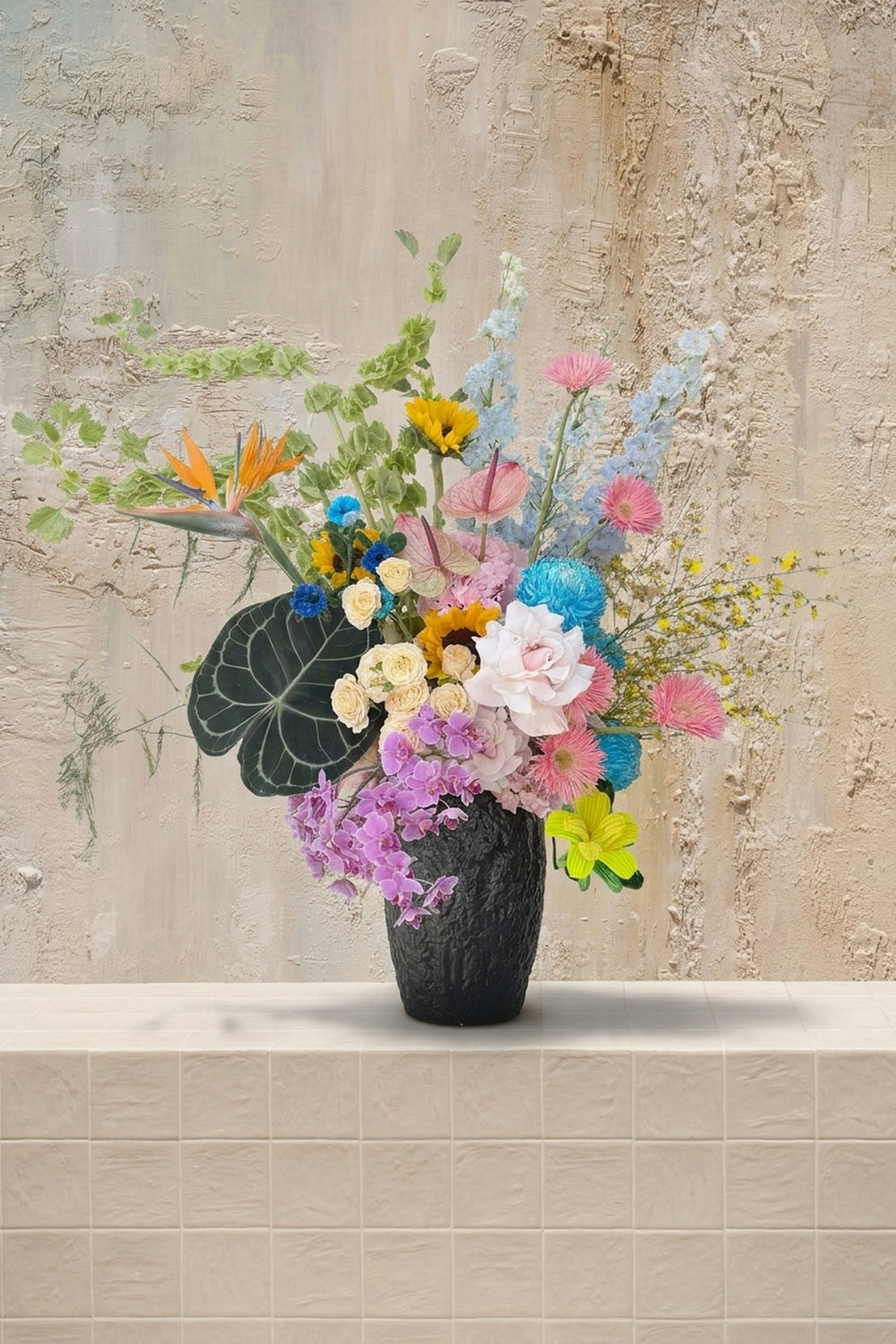 Sweet Love - orange Bird of Paradise, yellow sunflowers, blue delphinium, lavender orchids, and mixed roses in a dark textured vase by Amicis.