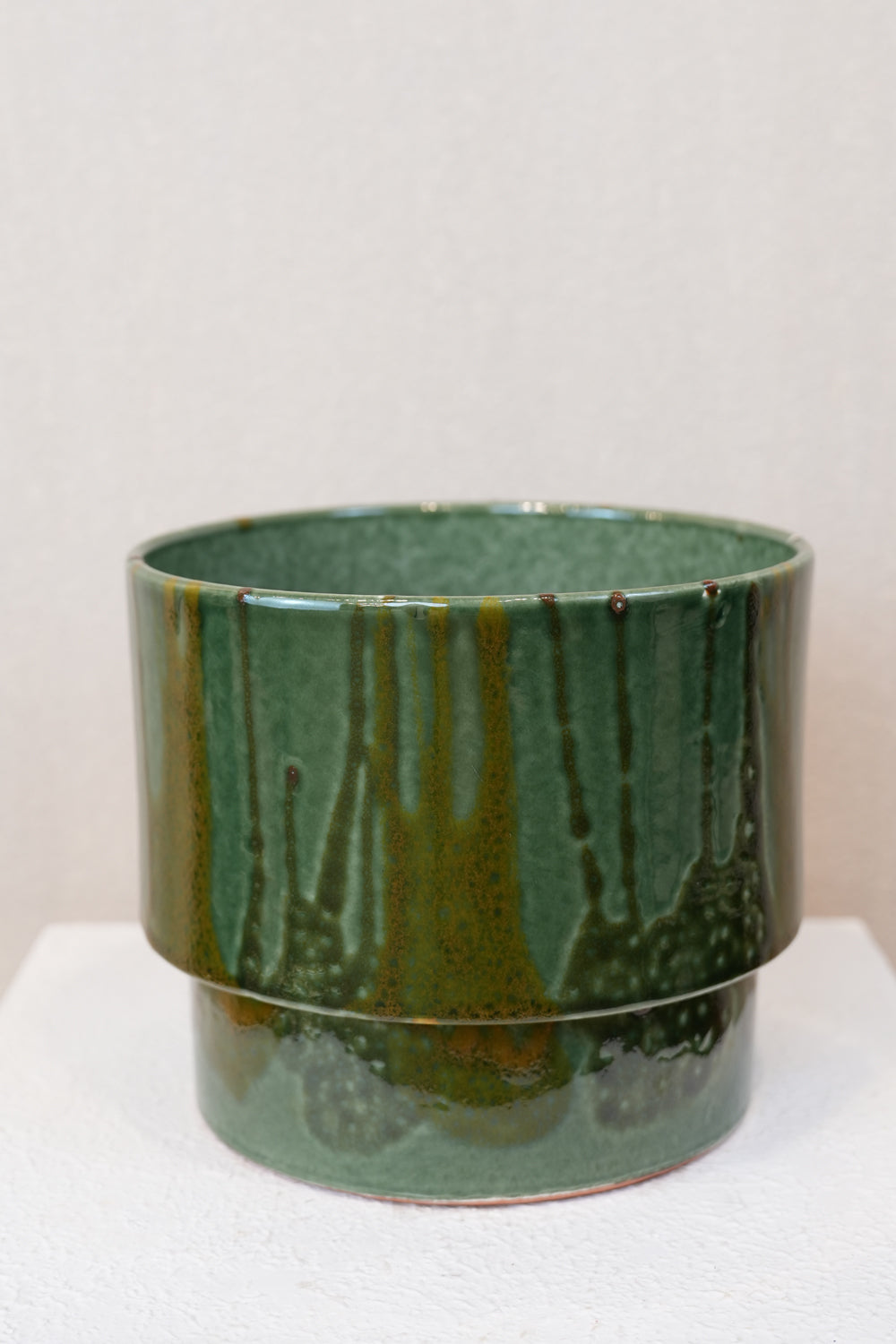 Green ceramic pot with a textured surface on a white background