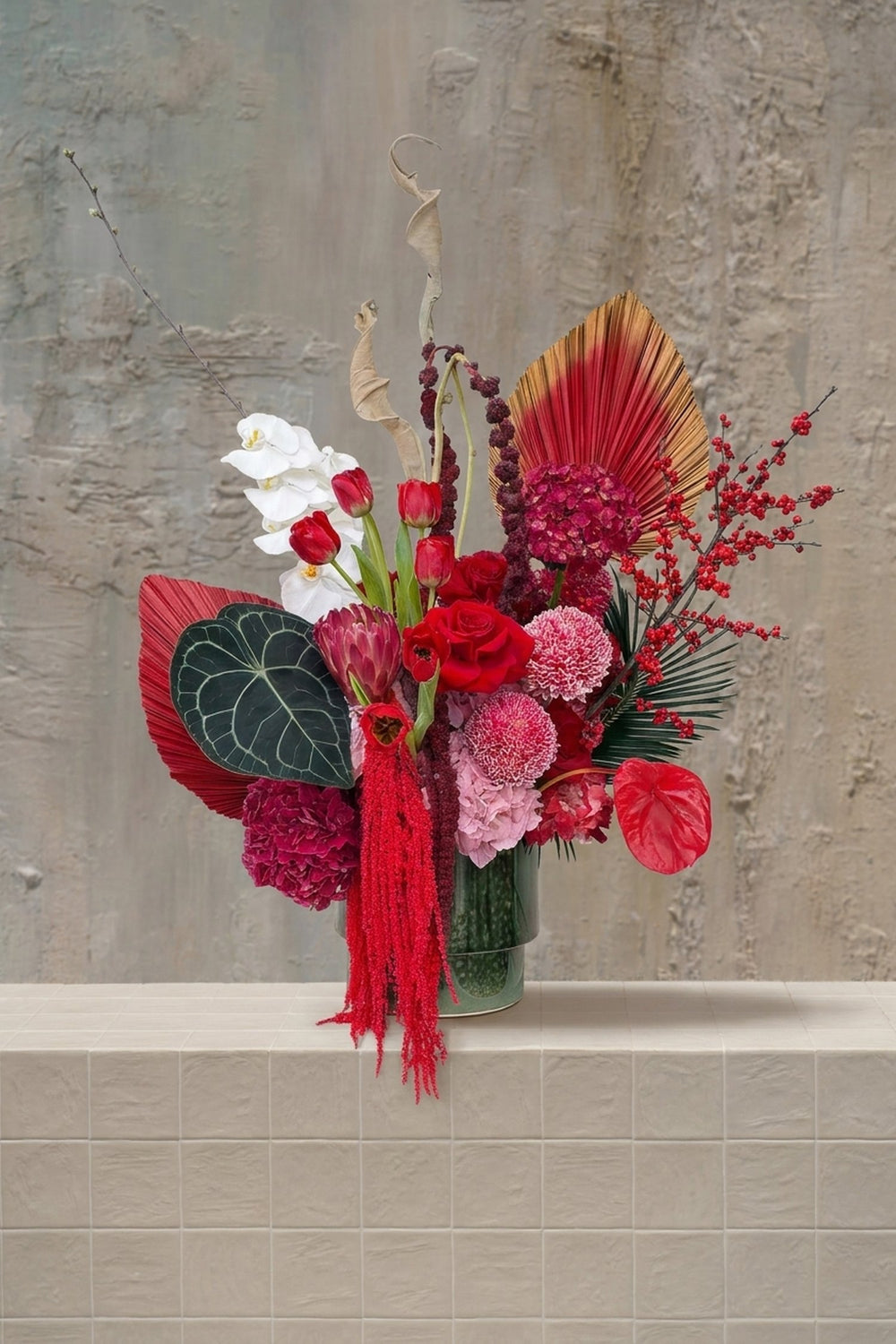 Velvet Stem - deep red roses, tulips, white orchids, fuchsia hydrangeas, anthurium, and amaranthus in a green glass vase by Amicis
