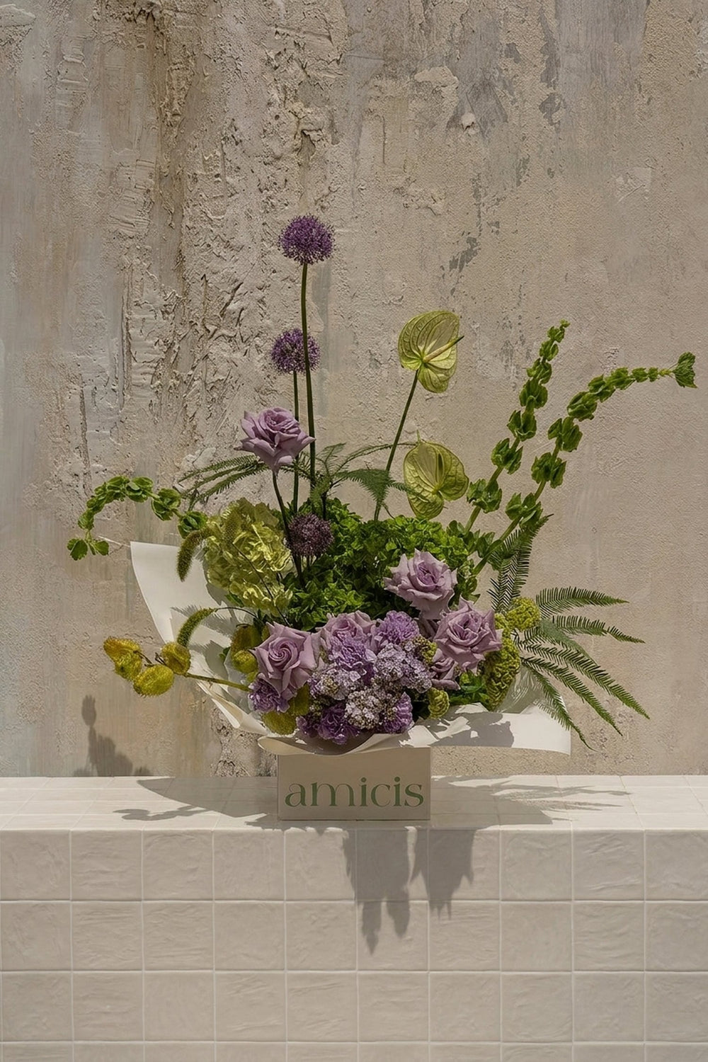 Vera 02 - lavender roses, purple alliums, green hydrangeas, anthurium, and bells of Ireland in a white floral box by Amicis